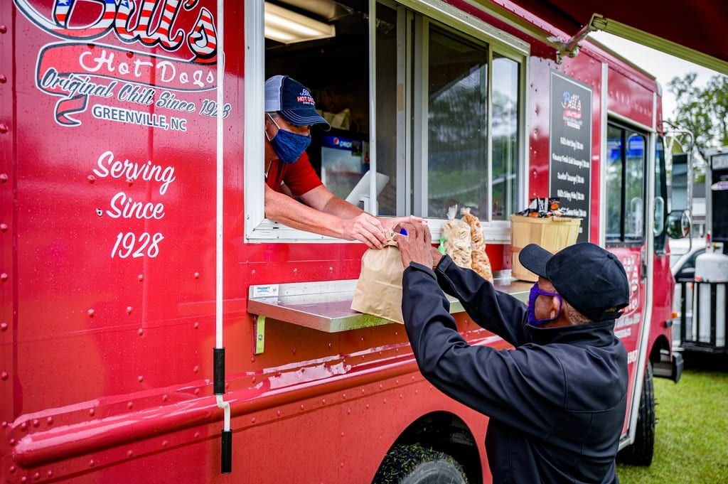 A customer picking up an order at a red food truck window